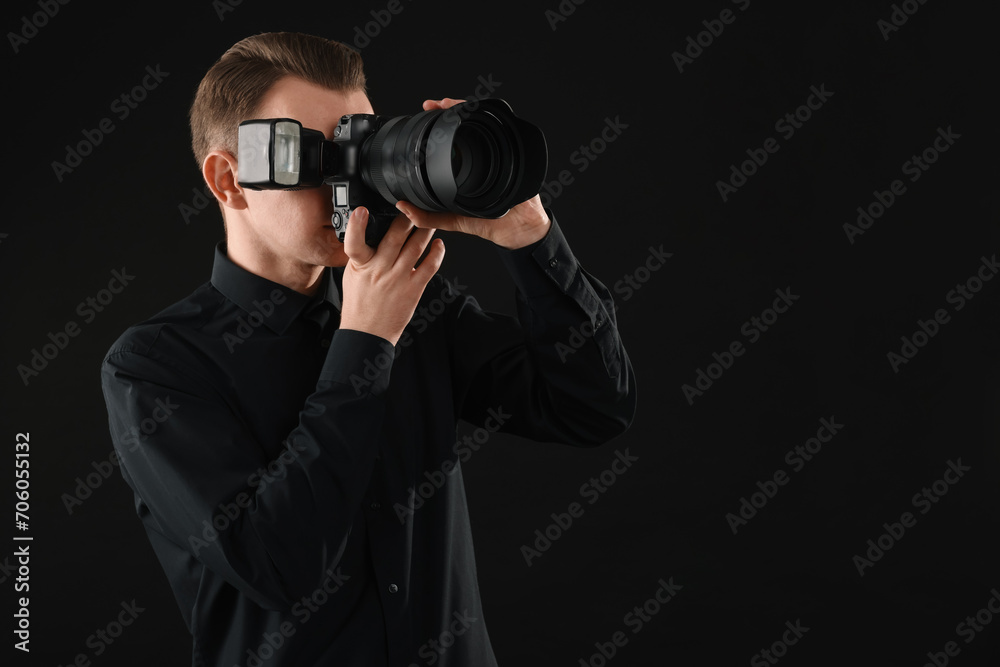 Professional photographer taking picture on black background, space for text