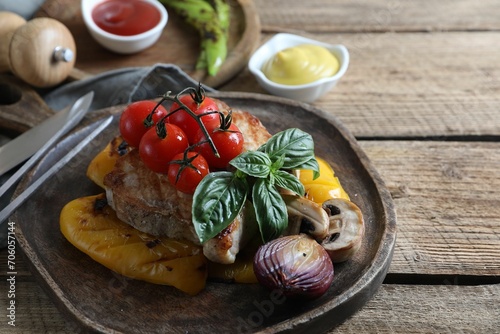 Delicious grilled meat and vegetables served on wooden table, closeup. Space for text