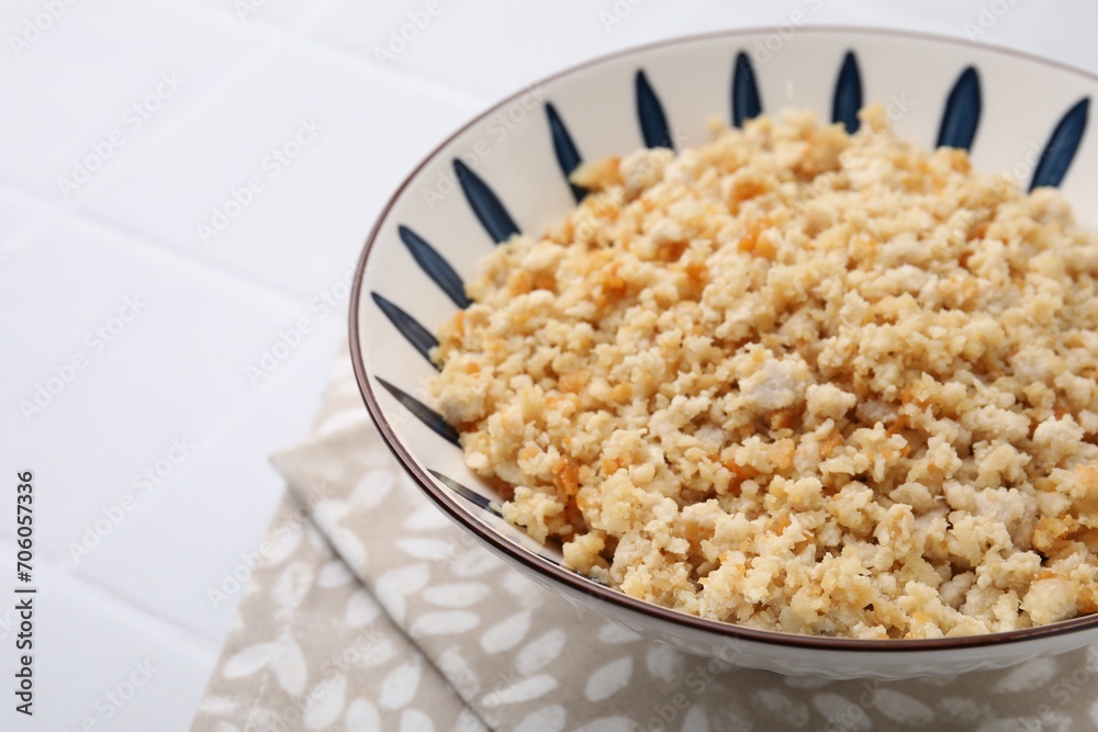 Fried ground meat in bowl on white tiled table, closeup. Space for text