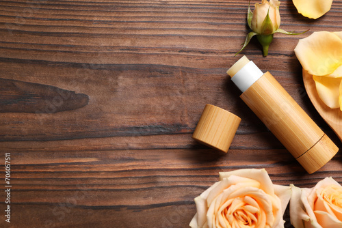 Lip balm and roses on wooden background, flat lay. Space for text photo