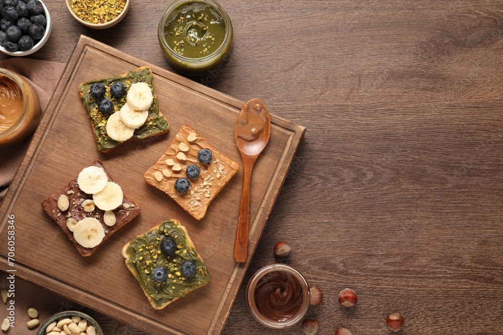 Toasts with different nut butters, blueberries, banana and nuts on wooden table, flat lay. Space for text Toasts with different nut butters, blueberries, banana and nuts on wooden table, flat lay. Space for text
