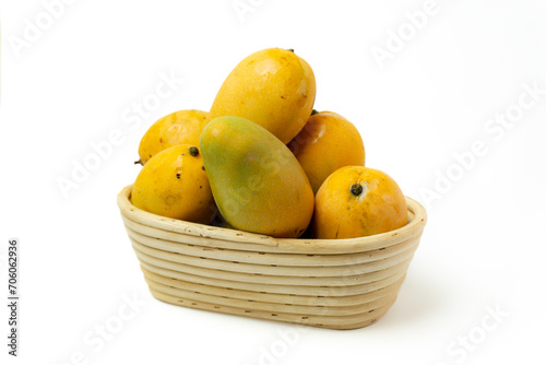 pile of ripe mango on a basket made of rattan, isolated on white background, top view