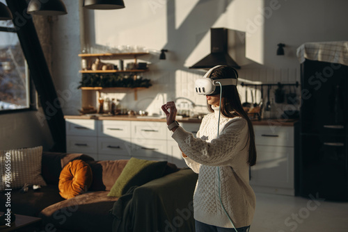 Playing an online game, a lovely young lady enjoys her VR headset in the apartment.