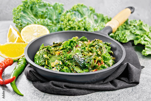 Kale cabbage with orange and pepper in pan on stone