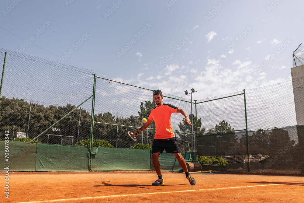 Man in sportswear playing tennis on a dirt tennis court