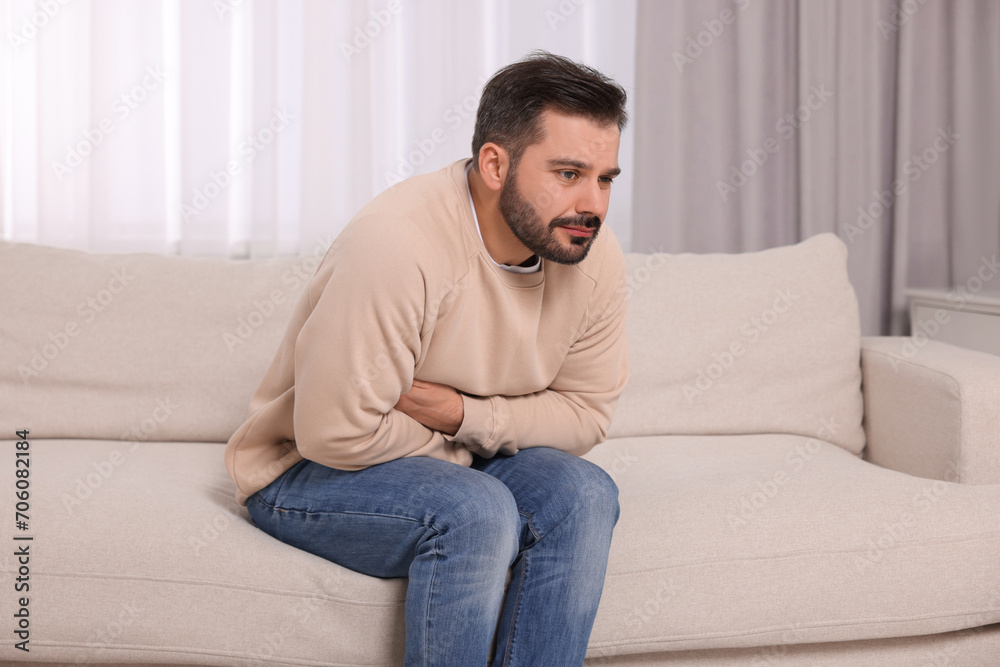 Man suffering from stomach pain on sofa at home