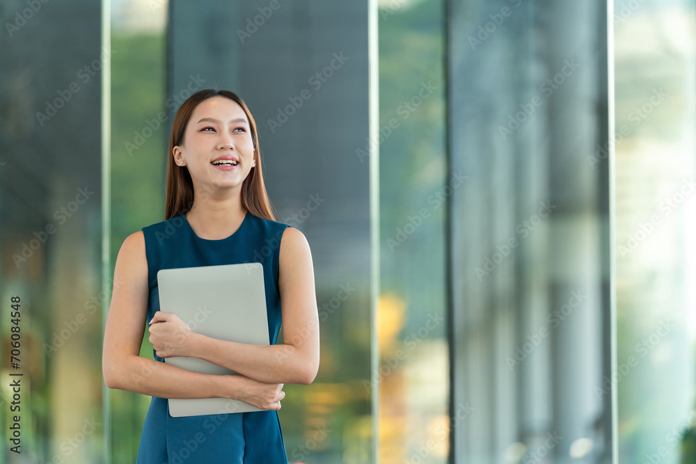 Portrait of an Asian Business Woman Holding a Laptop with a Elegant Look and Smile Portrait of an Asian Business Woman Holding a Laptop with a Elegant Look and Smile
