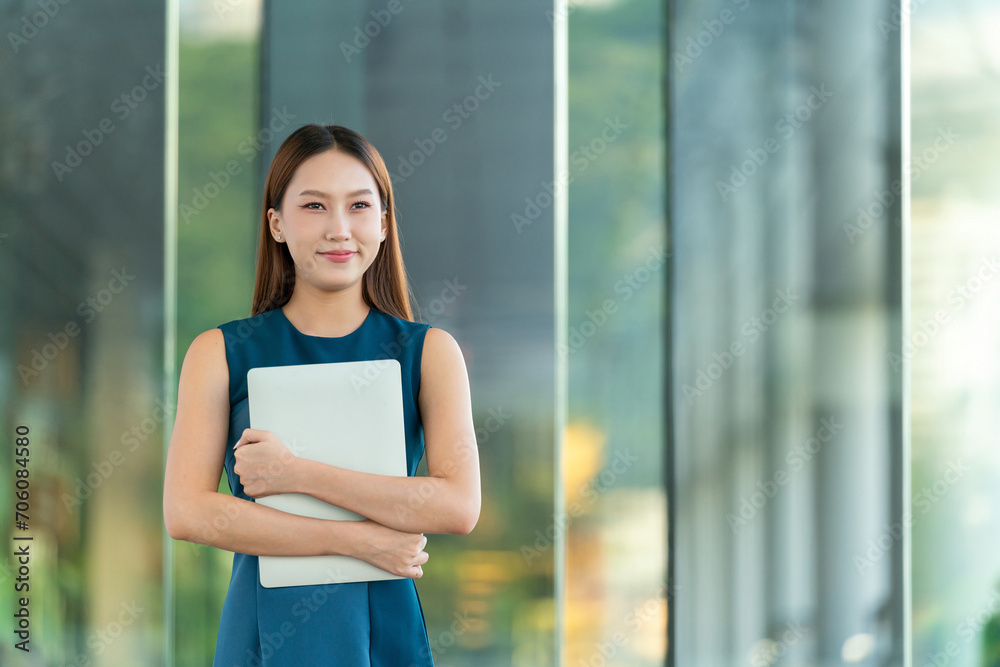 Portrait of an Asian Business Woman Holding a Laptop with a Elegant Look and Smile Portrait of an Asian Business Woman Holding a Laptop with a Elegant Look and Smile