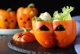 Bell pepper with black olives, mozzarella and lettuce as Halloween monster on dark table, closeup