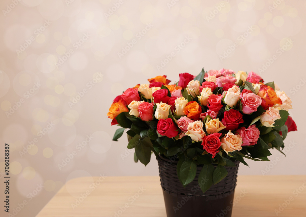 Fototapeta premium Bouquet of beautiful roses on wooden table against light background. Space for text