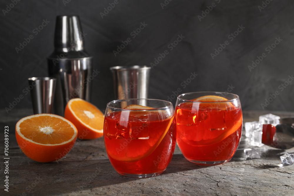 Aperol spritz cocktail, ice cubes and orange slices in glasses on grey textured table Aperol spritz cocktail, ice cubes and orange slices in glasses on grey textured table