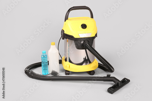 Vacuum cleaner with supplies on grey background
