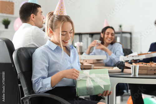 Young woman with gift at birthday party in office