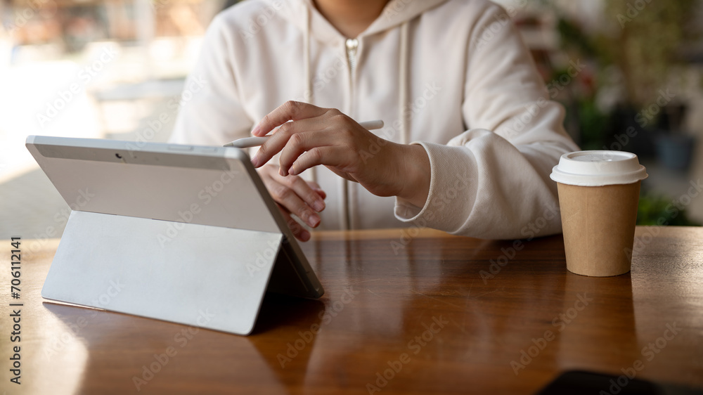 A female college student or a freelancer is using her digital tablet while sitting in a coffee shop. A female college student or a freelancer is using her digital tablet while sitting in a coffee shop.
