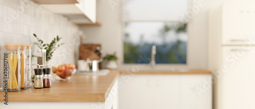 Side view of a wooden kitchen countertop with spice bottles  pasta bottles in a modern white kitchen