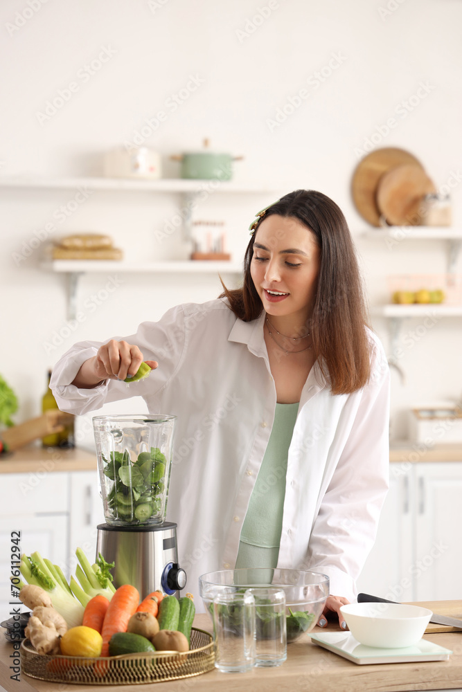 Young woman squeezing lime juice into blender in kitchen