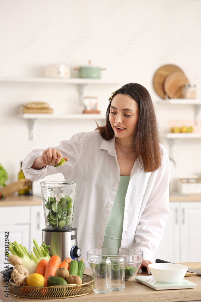 Young woman squeezing lime juice into blender in kitchen Young woman squeezing lime juice into blender in kitchen