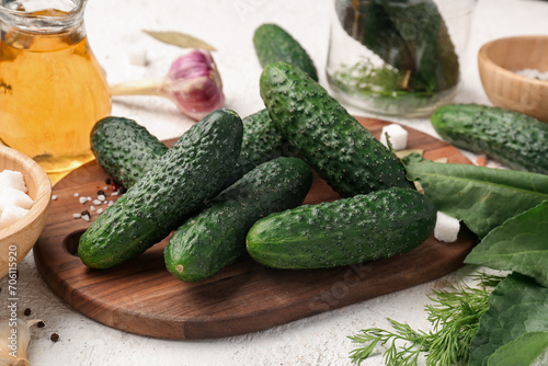 Wooden board with fresh cucumbers for preservation on light background