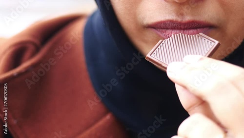 Closeup of woman eating chocolate candy , photo