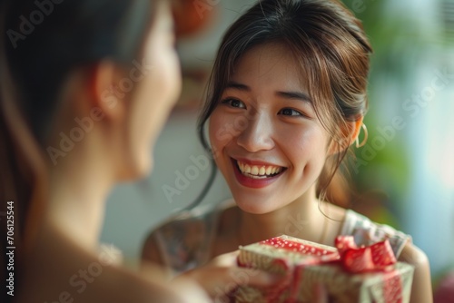 Excited Asian woman receives surprise gift from girlfriend at home Give a birthday present Birthday gift  New Year s Day