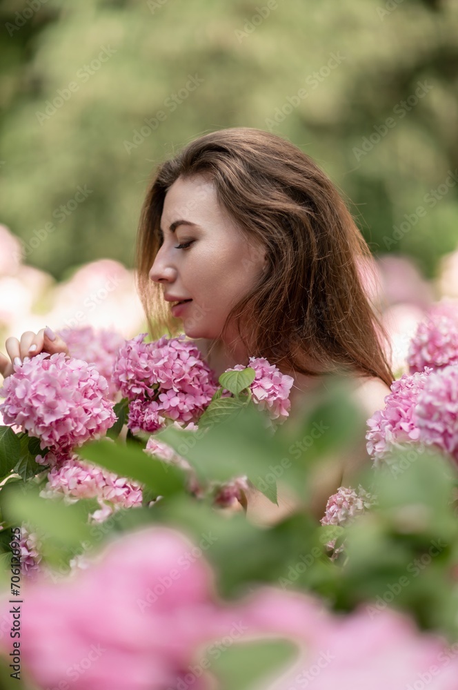Hydrangeas Happy woman in pink dress amid hydrangeas. Large pink hydrangea caps surround woman. Sunny outdoor setting. Showcasing happy woman amid hydrangea bloom. Hydrangeas Happy woman in pink dress amid hydrangeas. Large pink hydrangea caps surround woman. Sunny outdoor setting. Showcasing happy woman amid hydrangea bloom.
