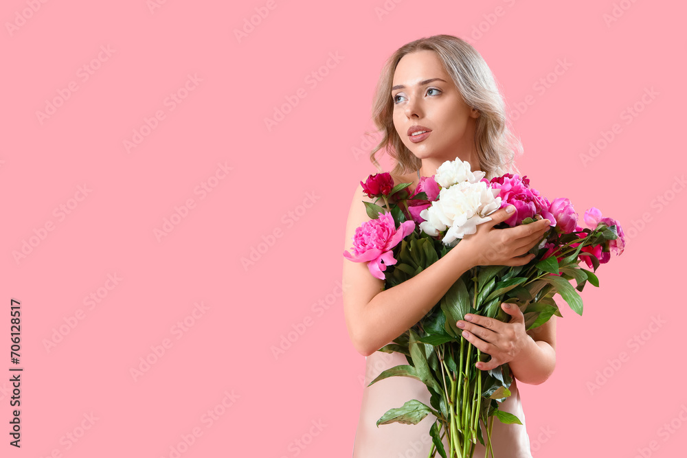 Young woman with beautiful peony flowers on pink background