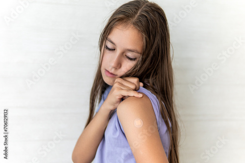 little girl showing her arm with bandage after virus vaccine. Kid and child vaccination campaign. Protect your kid with vaccine concept