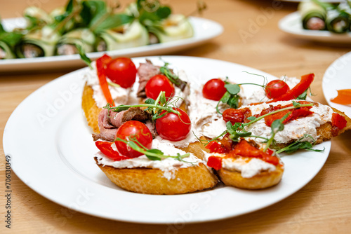 Bruschetta with Cream Cheese, Beef, and Cherry Tomatoes. Delicious bruschetta topped with cream cheese, succulent beef slices, fresh cherry tomatoes, and microgreens, arranged on a white plate.