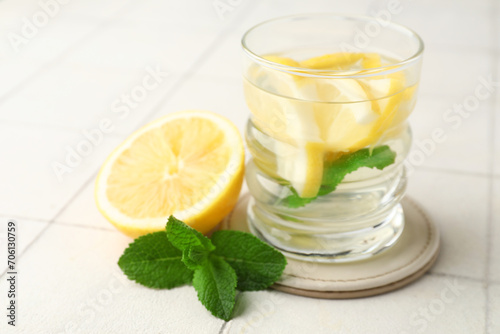 Glass of infused water with lemon and mint on white tile table