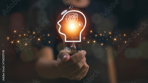 Hand holding a glowing lightbulb and human icon thinking for creative thinking ideas and problem-solving concepts.