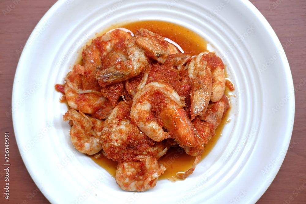 Schezwan Prawns in white plate with wooden background. Schezwan Prawns is indo-chinese cuisine curry dish with prawns or shrimps roasted in Schezwan Sauce. Udang saos Padang Schezwan Prawns in white plate with wooden background. Schezwan Prawns is indo-chinese cuisine curry dish with prawns or shrimps roasted in Schezwan Sauce. Udang saos Padang