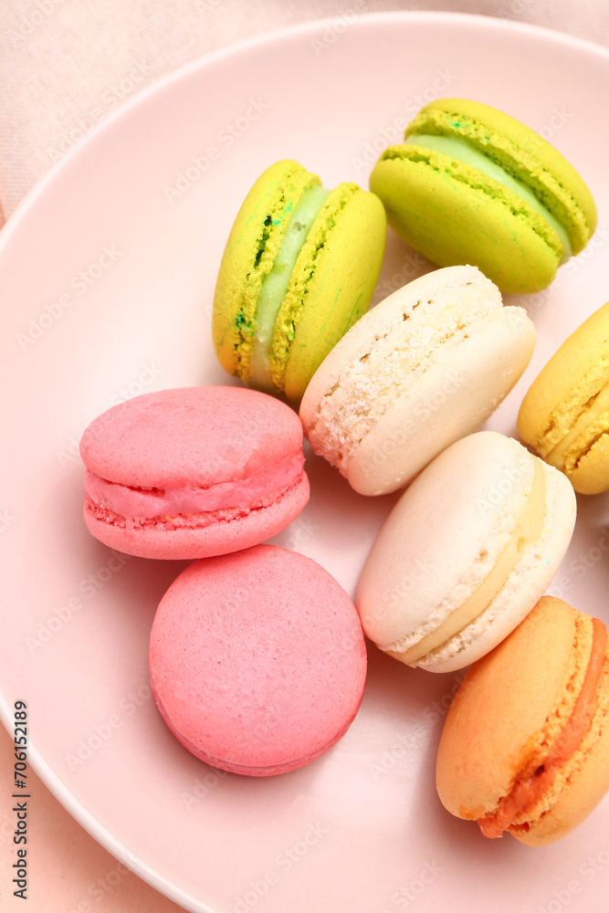 Fototapeta premium Plate with sweet macaroons on pink background, closeup