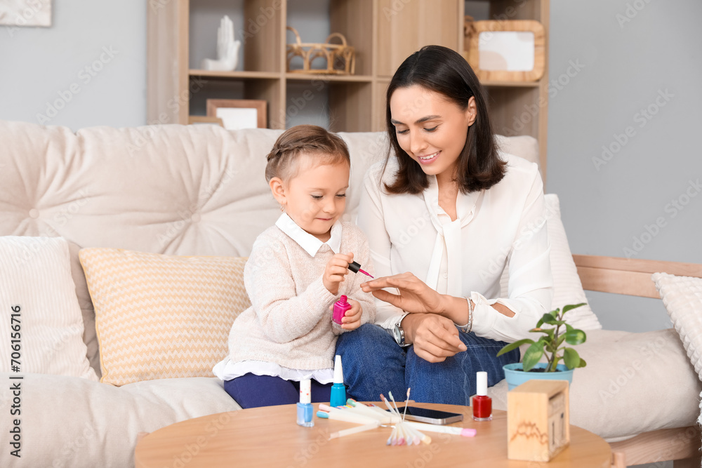 Cute little daughter doing nails of her beautiful mother at home Cute little daughter doing nails of her beautiful mother at home