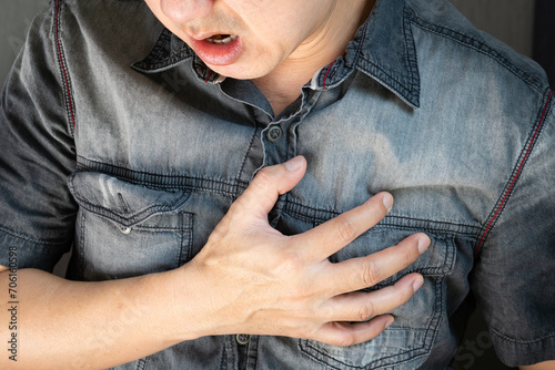Man is sick and in pain and uses his hands to squeeze his chest He had chest pain caused by an acute heart attack. medical and health concepts © Photo Sesaon