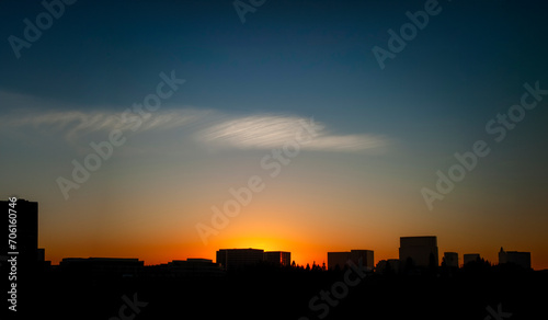 Silhouette of buildings at sunset with an interesting cloud. Most of the image is negative space.