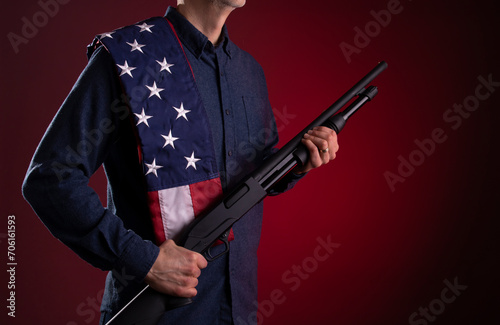 Armed citizen holding a shotgun with an American flag over his shoulder photo