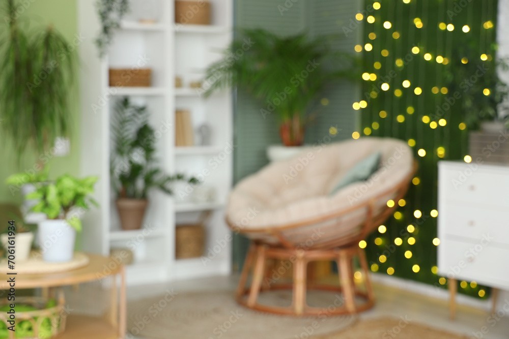 Obraz premium Blurred view of living room with green plants, armchair and glowing lights