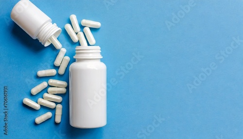 White Bottle and vitamin white capsules on skay blue background, top view