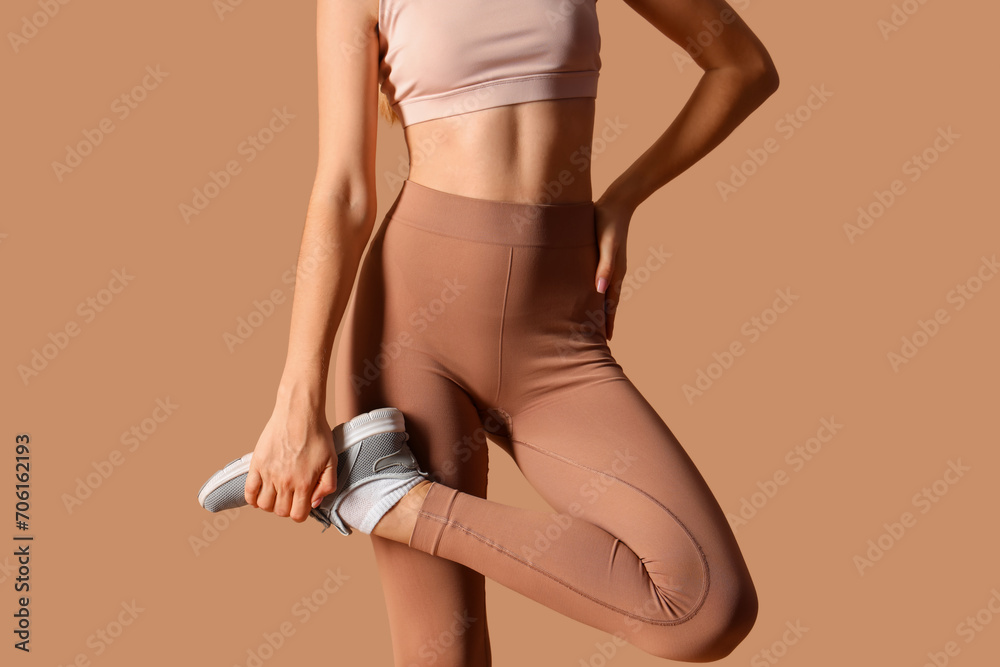 Sporty young woman in leggings on beige background - obrazy, fototapety, plakaty 