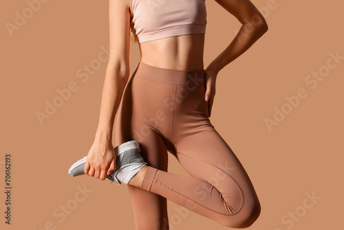 Sporty young woman in leggings on beige background photo