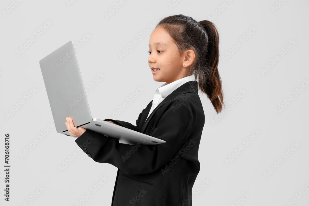 Cute little businesswoman working with laptop on light background. Opposite Day celebration Cute little businesswoman working with laptop on light background. Opposite Day celebration