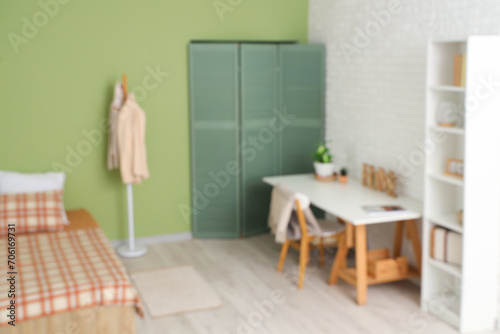Blurred view of bedroom with workplace and clothes rack