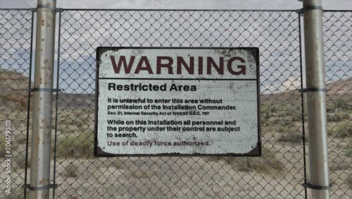 High quality 3D CGI render with a smooth dollying-in shot of a chainlink fence at a high security installation in a desert scene, with a Warning Restricted Area sign photo