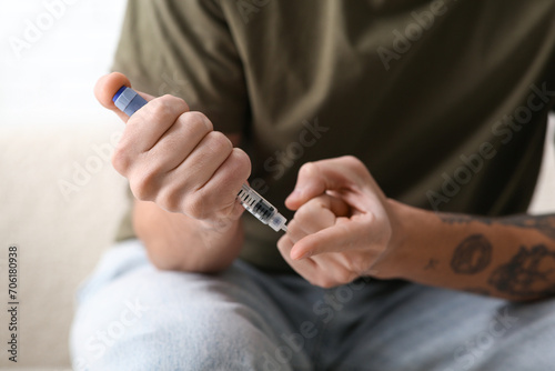 Diabetic young man using lancet pen at home  closeup