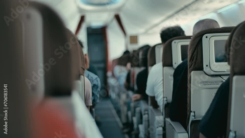 Passengers sit quietly on seats in the cabin of an airplane that is flying photo