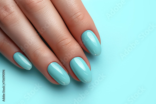 Female hand with mint manicure on blue background close-up.
