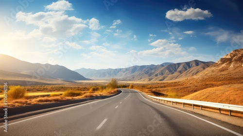 Asphalt road in the mountains under the blue sky with clouds.