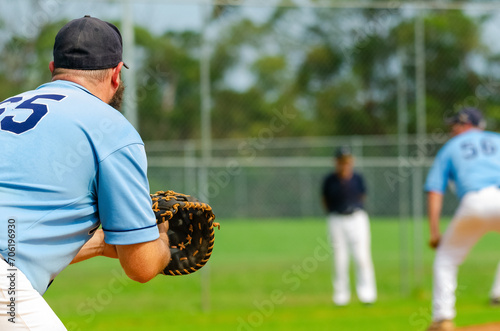 Baseball game, first baseman is getting ready to catch a ball from a pitcher, base coach in the background.