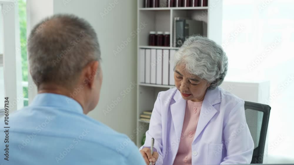 An elderly Asian male patient answers questions from an elderly female doctor. health advice and discuss comprehensive health care in a healthcare environment. Health insurance concept. An elderly Asian male patient answers questions from an elderly female doctor. health advice and discuss comprehensive health care in a healthcare environment. Health insurance concept.