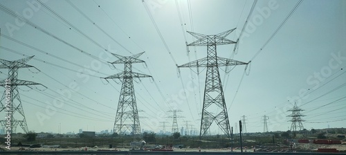 Group or bunch of tall electrical power transmission or electricity energy distribution pole, tower or grid with high voltage cable wires. Pylon line electric supply in united arab emirates concept.